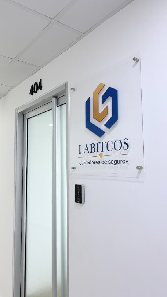 Entrada de la oficina LABITCOS, corredores de seguros, con el letrero corporativo junto a la puerta