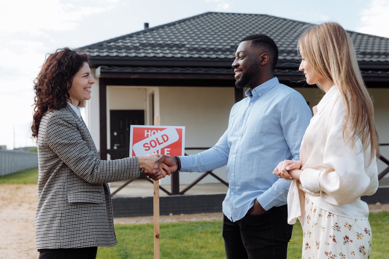 services-02 Real estate agent sealing a deal with a diverse couple in front of their new house.